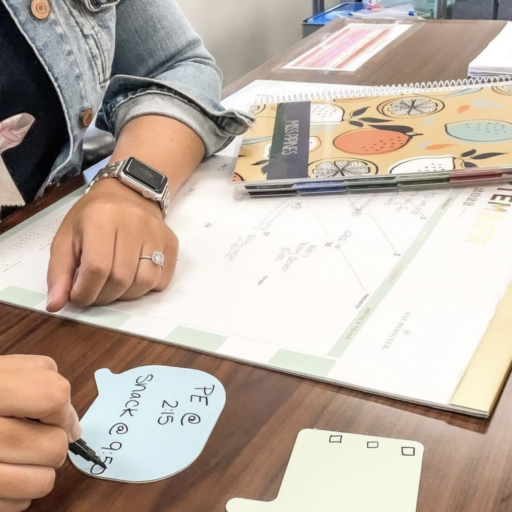 teacher with personalized teacher planner cover on desk planning
