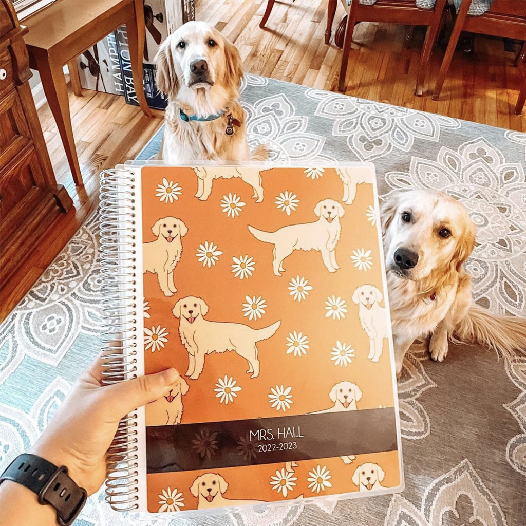 teacher holding personalized teacher planner cover with dogs in background